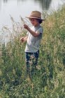 Хлопчик стоїть в траві на озері — стокове фото