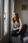 Femme tatouée assise à la fenêtre — Photo de stock