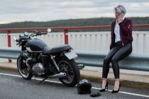 Donna che parla sullo smartphone accanto alla moto — Foto stock