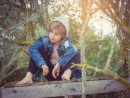 Little boy sitting on wooden pier — Stock Photo