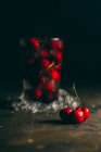 Fresh cherries and glass with ice — Stock Photo