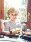 Маленький хлопчик з чашкою сидить за столом — стокове фото