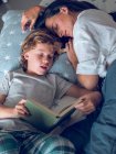 Мать спит и сын читает книгу — стоковое фото
