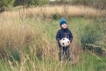 Хлопчик стоїть з футбольним м'ячем — стокове фото