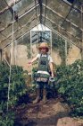 Niño regando plantas en invernadero - foto de stock