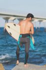 Mann mit Surfbrett steht an Küste — Stockfoto
