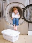 Mignon élémentaire âge garçon assis à l'intérieur machine à laver — Photo de stock