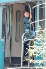 Хлопчик сидить на поручнях поїзда — стокове фото