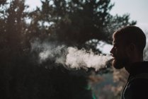 Homem barbudo fumando na floresta — Fotografia de Stock