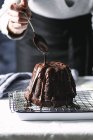 Mão derramando chocolate no bolo bundt — Fotografia de Stock