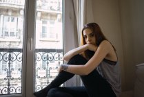 Татуированная женщина, сидящая у окна — стоковое фото