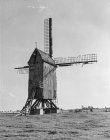 Schwarz-weiße Ansicht einer verwitterten hölzernen Windmühle im belgischen Feld im Sonnenlicht. — Stockfoto