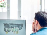 Hombre sin rostro modelando dentadura postiza en computadora - foto de stock