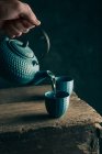 Hand gießt Tee in Tasse — Stockfoto