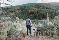 Homme avec chien marchant dans la forêt — Photo de stock