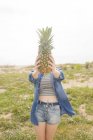 Woman holding pineapple in front of face — Stock Photo