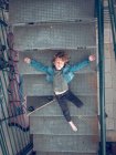 Niño acostado con monopatín en las escaleras - foto de stock
