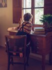 Мальчик, сидящий на стуле за столом — стоковое фото