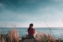 Женщина сидит и смотрит на морской пейзаж — стоковое фото