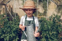 Niño sosteniendo regadera en invernadero - foto de stock