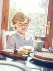 Маленький мальчик с чашкой сидя за столом — стоковое фото