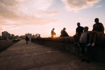Kubanische Stadtbewohner chillen bei Sonnenuntergang auf der Betonpromenade — Stockfoto