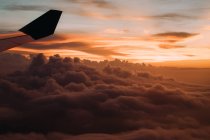 Dramatic sky with clouds and plane wing at sunset — Stock Photo