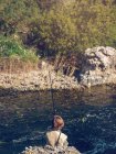 Niño sentado y pescando - foto de stock