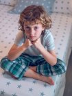 Boy sitting on bed — Stock Photo
