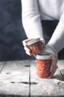 Hands holding jars of jam — Stock Photo