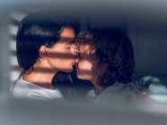 Mother kissing son in sunlight — Stock Photo