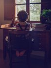 Мальчик, сидящий на стуле за столом — стоковое фото