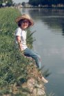 Little boy swinging legs above water — Stock Photo
