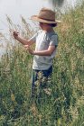 Мальчик, стоящий в траве у реки — стоковое фото