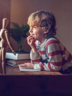 Мальчик сидит с книгой за столом — стоковое фото