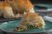 Pezzo di tradizionale torta di spinaci greci spanakopita su piatto blu — Foto stock