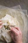 Mãos humanas preparando torta de spanakopita tradicional no papel manteiga — Fotografia de Stock