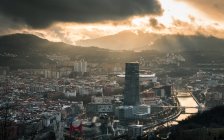 Rascacielos moderno y casco antiguo bajo el cielo nublado - foto de stock