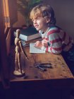 Хлопчик сидить з книгою за столом — стокове фото