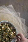 Menschliche Hand rührt Füllung für traditionelle Spanakopita-Spinatkuchen in Schüssel — Stockfoto