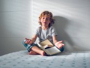 Menino de pijama sentado com livros — Fotografia de Stock
