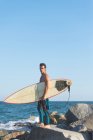 Homme avec planche de surf debout sur la côte — Photo de stock