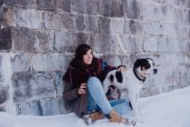 Женщина, опирающаяся на стену с собакой — стоковое фото