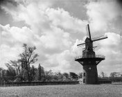 Vista em preto e branco do moinho de vento de madeira desgastado colocado no campo da Bélgica sob a luz solar . — Fotografia de Stock