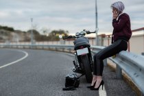 Mulher falando no smartphone ao lado de moto — Fotografia de Stock