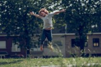 Возбужденный мальчик прыгает выше травы — стоковое фото