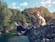 Мальчик сидит и рыбалка — стоковое фото