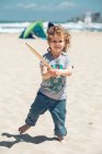 Мальчик с деревянной ракеткой на пляже — стоковое фото