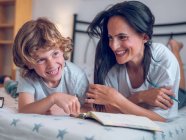 Woman and son lying on bed — Stock Photo