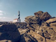 Rocky hill and lighthouse — Stock Photo
